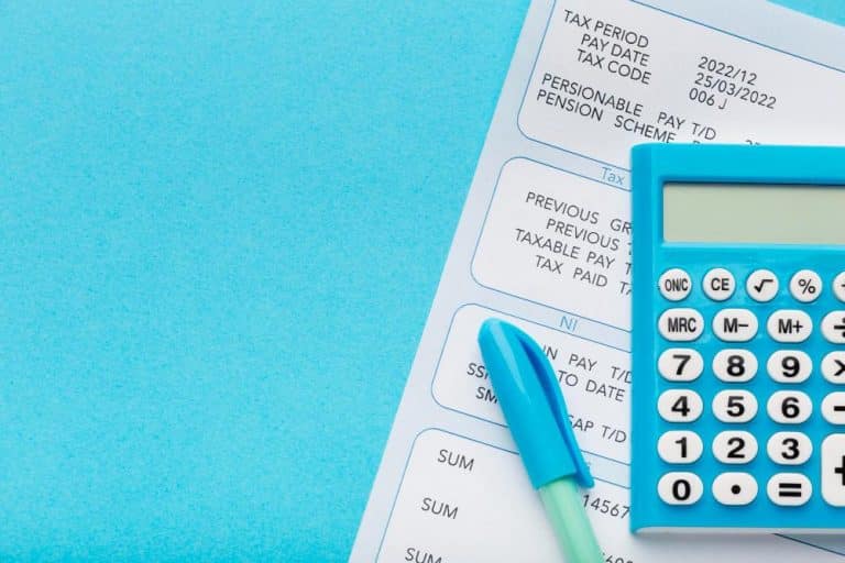 Tax forms with a bright blue calculator and blue pen on a blue background, suggesting tax filing or budgeting activity